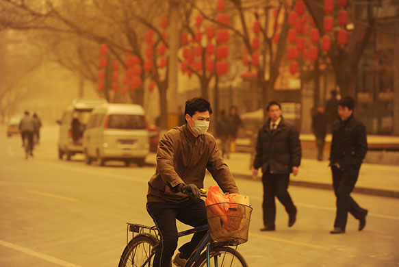 Sandstorms in China: A man cycles during a sandstorm in Beijing 