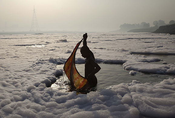 24 hours in pictures: A Hindu wraps his cloth after a ritual dip in the polluted Yamuna river