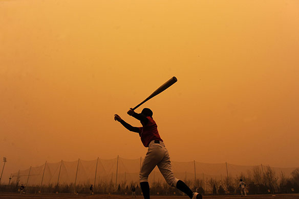 24 hours in pictures: Beijing, China: A softball player hits a ball during a sandstorm 