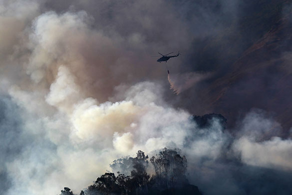 24 hours in pictures: A helicopter drops water over a wild forest fire 