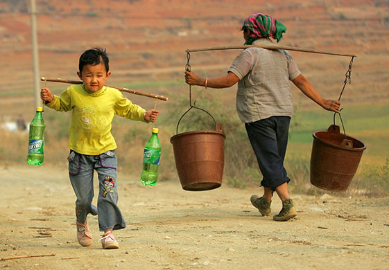 24 hours in pictures: A boy carries plastic bottles filled with water 