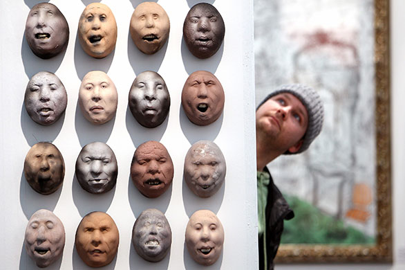 24 hours in pictures: Glasgow, UK: A exhibitor views ceramic heads at Glasgow Art Fair