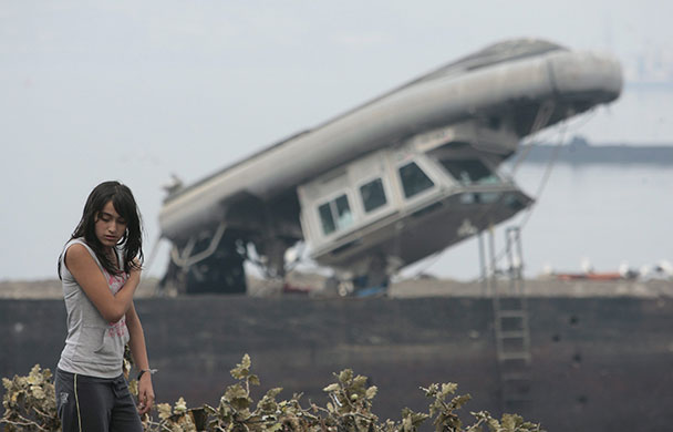 Chile security: A woman walks near the destroyed harbour at the port city of Talcahuano