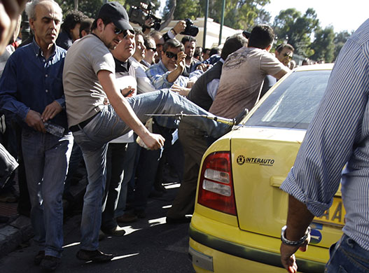 Greece protests: Taxi drivers kick the cab of a colleague, Athens, Greece