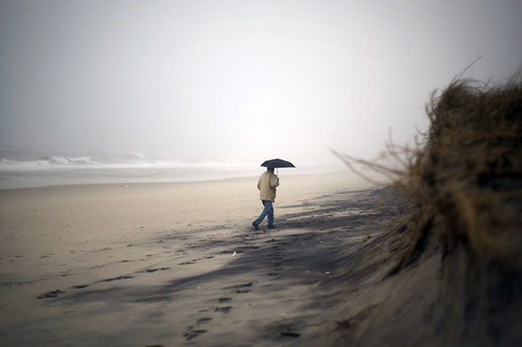 24 hours in pictures: Babylon, US: A beachgoer walks along an eroded section of a beach