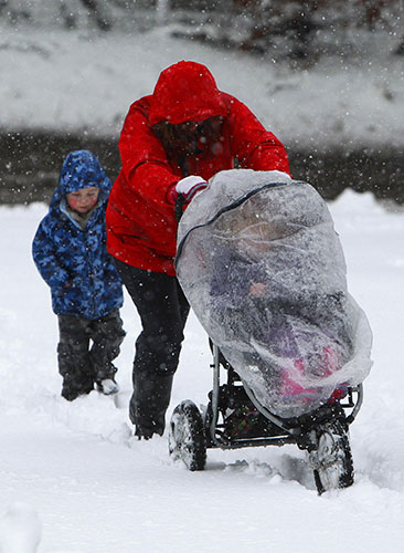 Snow in Scotland: A mother struggles to push a pram up a snow covered pavement in Dunblane