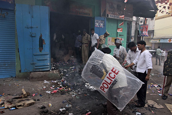 24 hours in pictures: Hyderabad, India: Policemen try to douse a fire after a shop was set alight