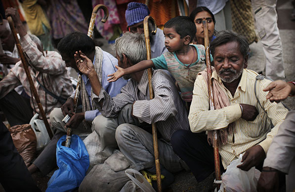24 hours in pictures: New Delhi, India: An child reaches between blind men begging for charity