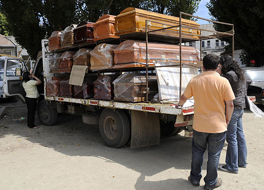 Chile Aid: Municpal employees check coffins next to a hospital in Constitucion, Chile