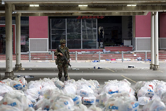Chile Aid: A Chilean soldier protects bags of supplies from looters at a supermarket
