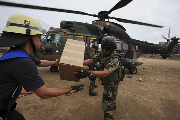 Chile Aid: Troops and firefighters unload aid from military helicopter, Dichato, Chile