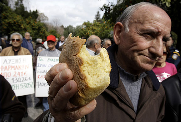 Week in business: A pensioner holds up bread during a demonstration in Athens