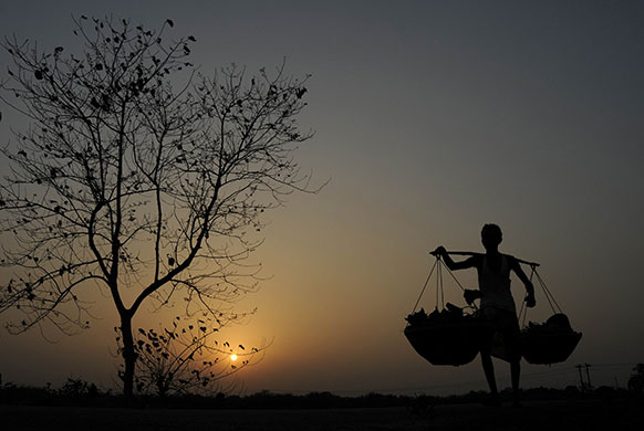 24 Hours in Pics: A vendor carries vegetable baskets on the outskirts of Agartala
