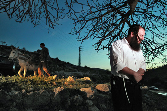 24 hours in pictures: Palestinian man passes praying Jew in Jerusalem