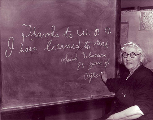 New Deal: An eighty year old woman stands proudly by a blackboard