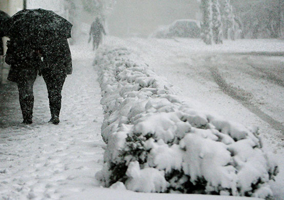 snow in barcelona: People walk along a road covered by snow 