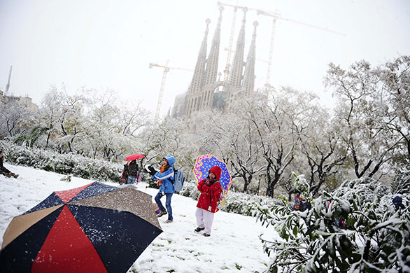 snow in barcelona: Children play in front of Antoni Gaudi's La Sagrada Familia