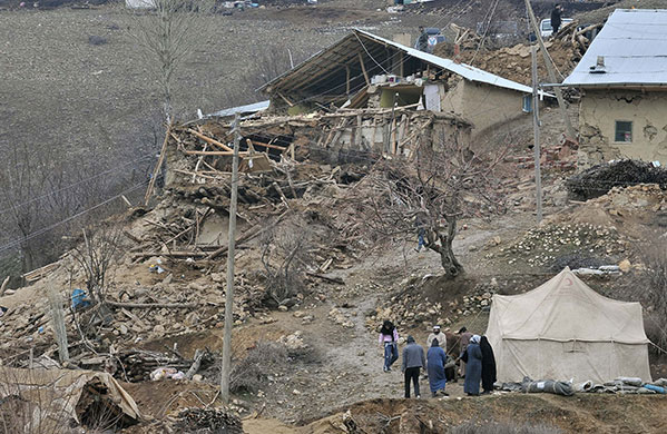 Turkey earthquake: People walk in the debris of houses destroyed in an earthquake in Okcular
