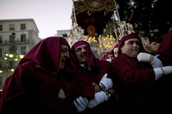 Holy week: A foreman helps a penitent as he carries the statue in Malaga