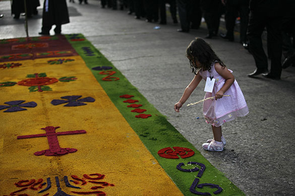 Holy week: Guatemala City, Guatemala: A girl drops flower petals on a carpet