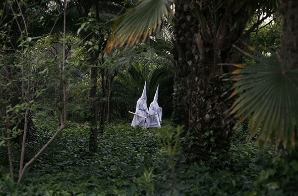 Holy week: Seville, Spain: Penitents walk after taking part in a procession