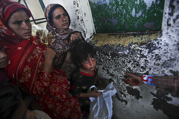 24 Hours in Pics: Pakistani women and children stand in a line as they wait to get rice