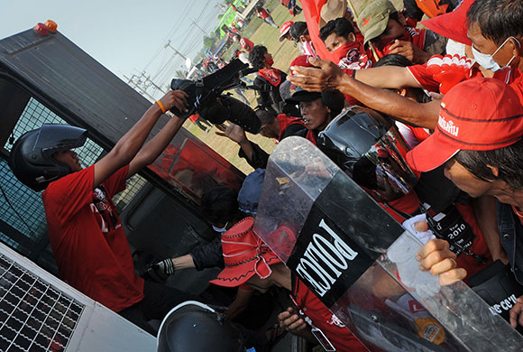 Riots in Thailand: Red Shirt protesters loot weapons from a police vehicle in Bangkok