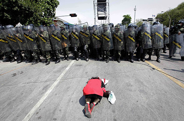 Riots in Thailand: An 'red shirt' protester prays in front of the security force in Bangkok