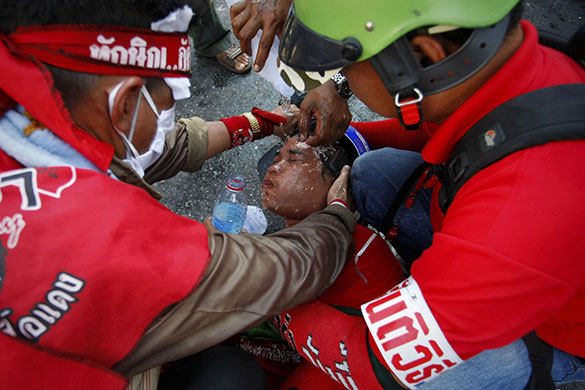 Riots in Thailand: Anti-government demonstrators wash tear gas from the eyes of a companion