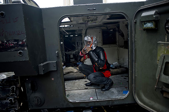 24 hours : Bangkok, Thailand: A protester wearing a gas mask sits in an army vehicle