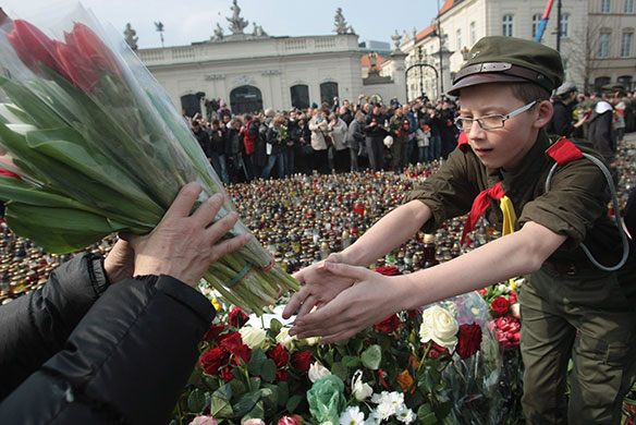 Poland in mourning : A young boy takes a floral tribute at the gate of the Presidential Palace