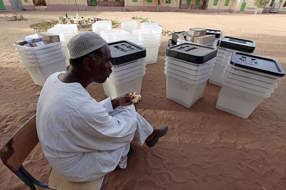 Sudan elections: A Sudanese worker eats beside polling boxes at a polling station 