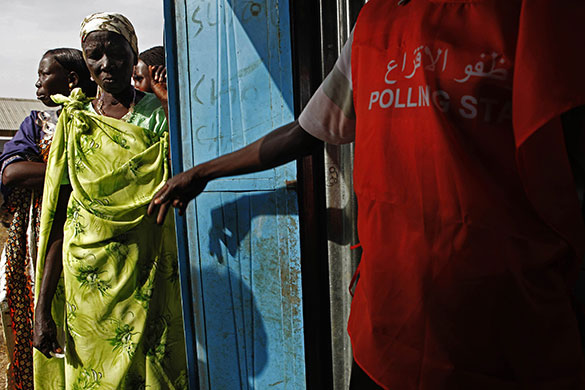Sudan elections: An election official calls a voter into a polling station 