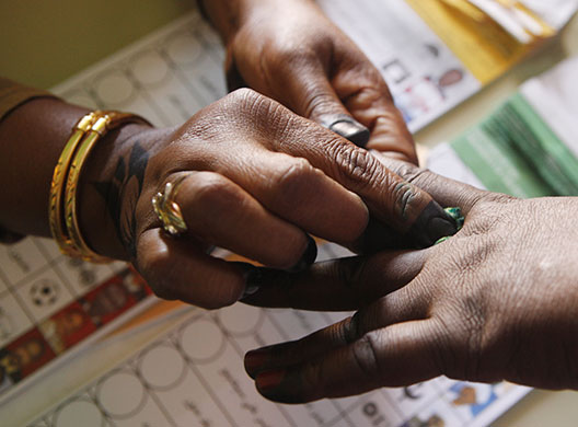 Sudan elections: A Sudanese polling station staff member stains a voter's fingers