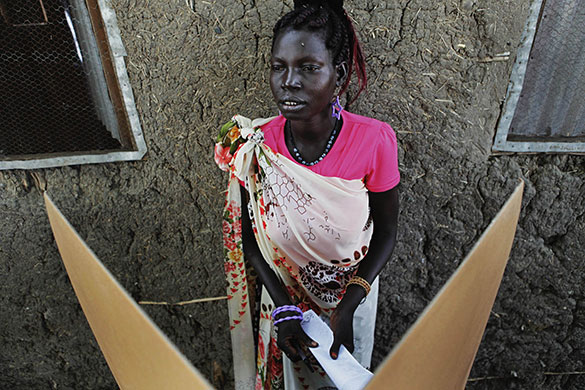 Sudan elections: A Sudanese woman folds her ballot behind a cardboard screen
