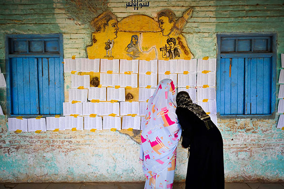 Sudan elections: Two women look through the list of voters at a polling station in Khartoum