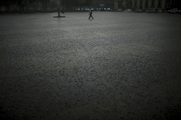 24 hours in pictures: Guatemala City, Guatemala : A man crosses a park in heavy rain