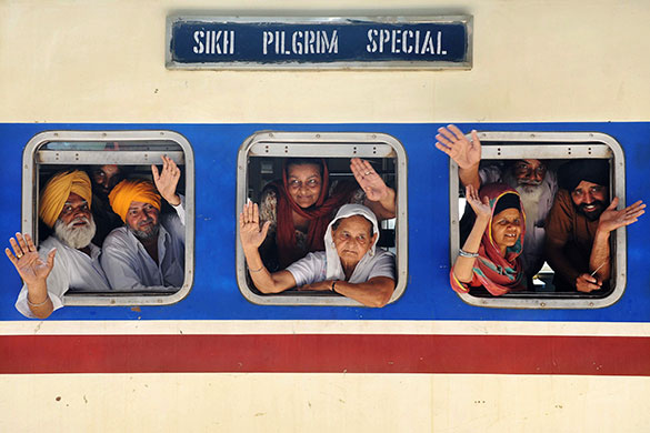 Sikh festivals: Indian Sikh pilgrims wave after boarding a train for Pakistan 