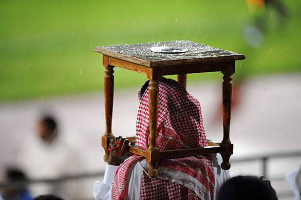 24 hours in pictures: Kuwait: A football fan protecting himself from the rain