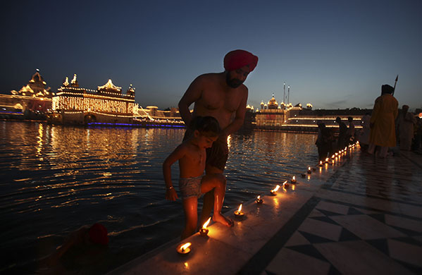 Sikh festival: A Sikh devotee and his child emerge after taking a dip in the holy pond