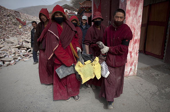 china earthquake: Tibetan monks carry the body of a woman in Jiegu