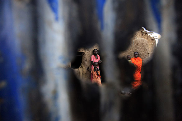 24 hours: Khartoum, Sudan: Women stand behind a door of their house on the outskirts