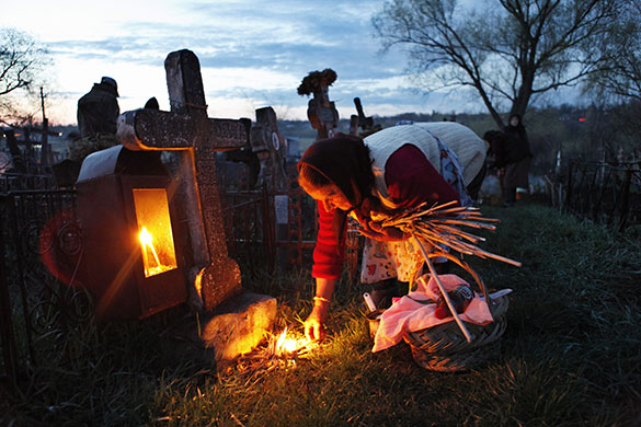 24 hours: Naipu, Romania: An elderly woman lights a fire at her family's grave