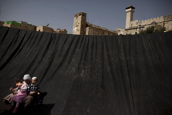 24 hours: Hebron, West Bank: An orthodox Jewish woman sits with her children
