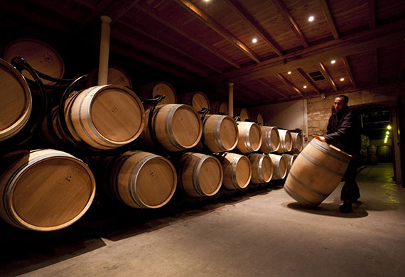 Wine tasting in Bordeaux: Moving a barrel in the Chais (wine cellars) at Château Beychevelle 