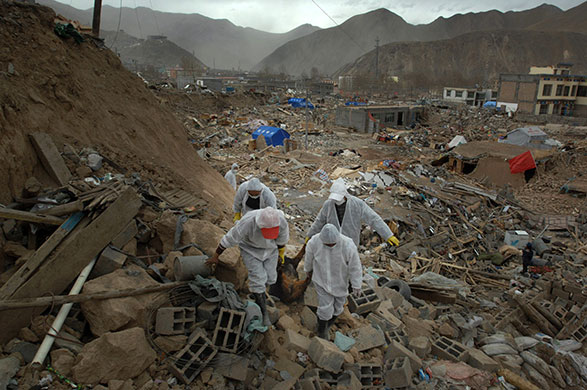 China earthquake: Rescue workers remove a body from the rubble of buildings in Jiegu