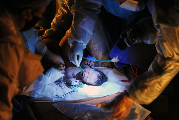 24 hours in pictures: Yushu County, China: Nurses deliver a baby at a makeshift shelter 