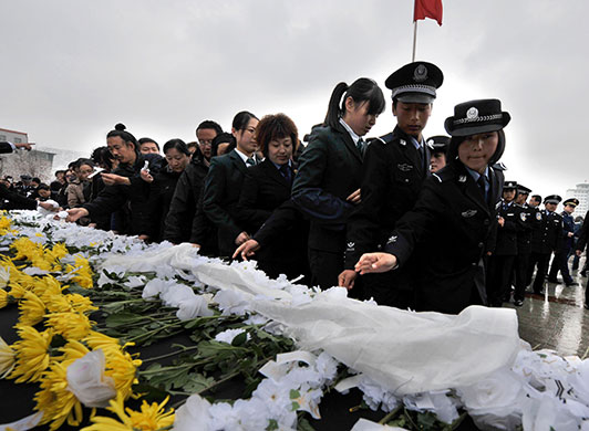 china quake mourning: Xining: Police place flowers as they take part in a mourning ceremony