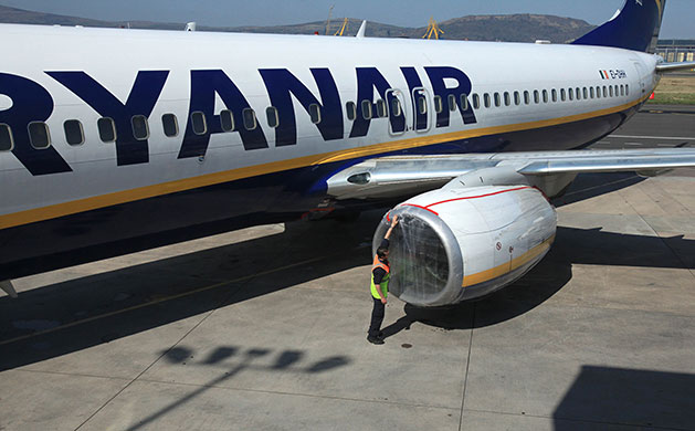 Week in Business: Ground staff secure a plastic cover on the engine of a Ryanair plane