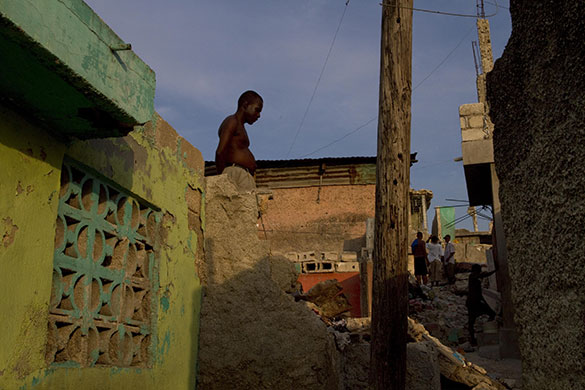 24 hours in pictures: Port-au-Prince, Haiti: A man stands on the remains of a damaged hom